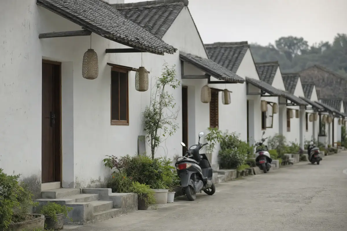 A row of near identical small guesthouses with tiled roofs along a village road