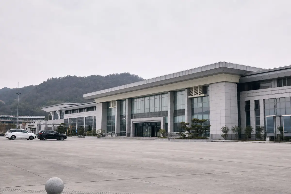 The forecourt of a small modern Chinese high-speed railway station under overcast light