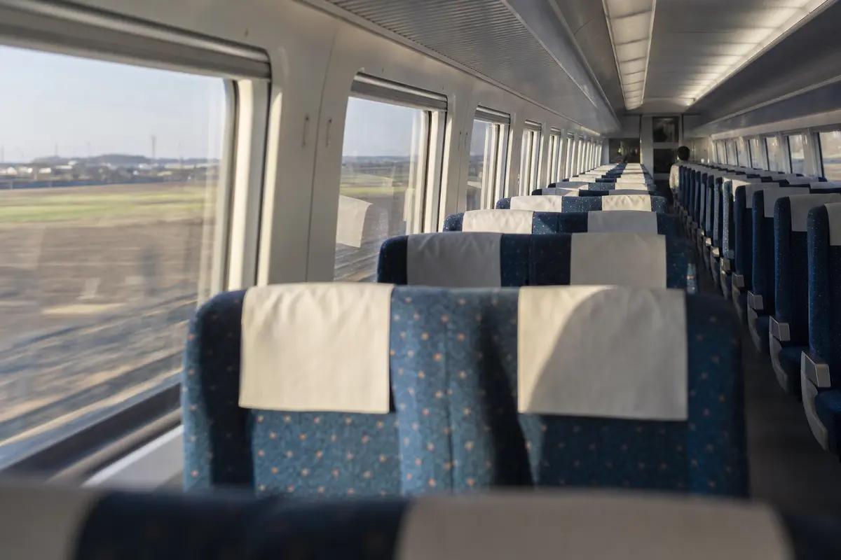 The interior of a high-speed train carriage with farmland blurring past the window