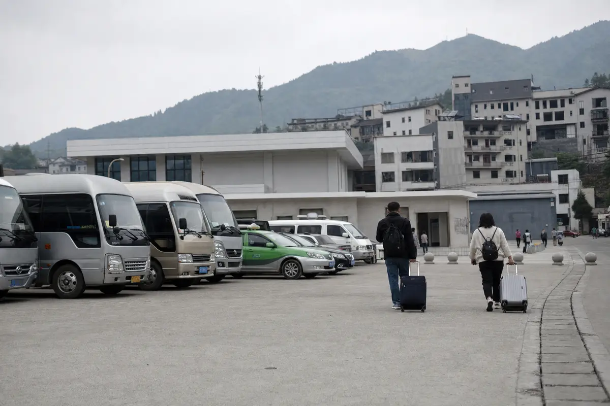 Minibuses and taxis lined up outside the exit of a small Chinese station