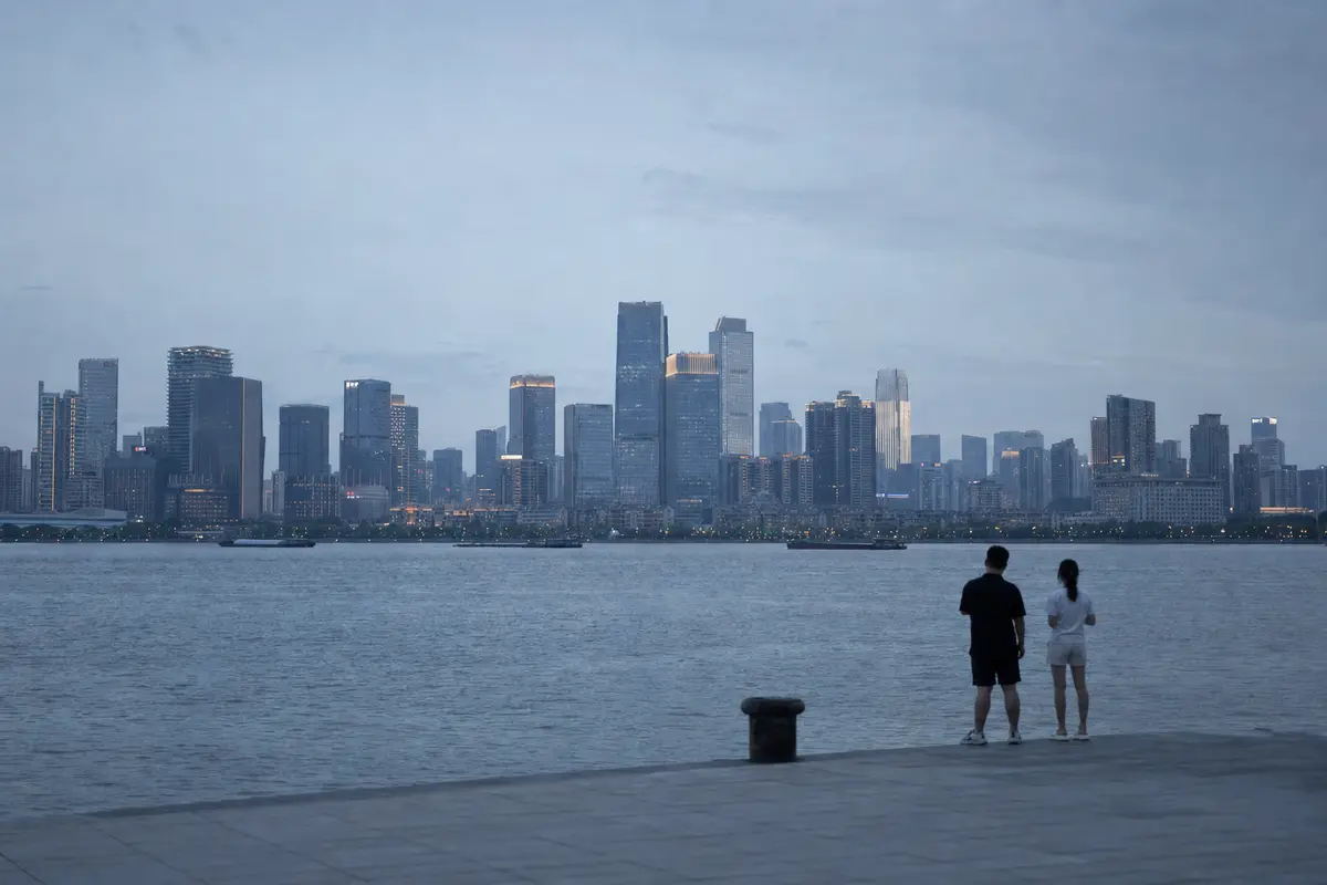A dense city skyline at dusk seen across dark water