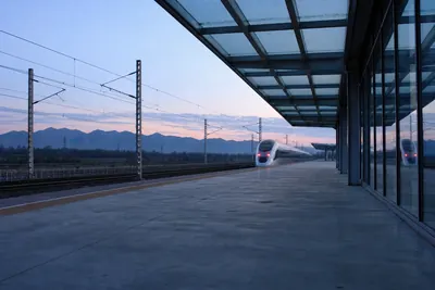 An empty Chinese high-speed rail platform before dawn, with a single train waiting at the far end