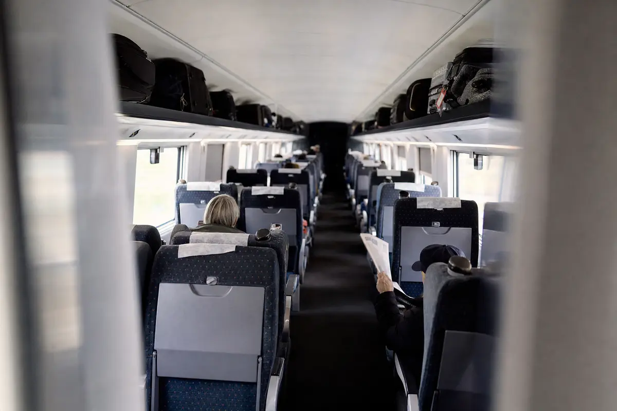 The aisle of a high-speed train carriage with full luggage racks
