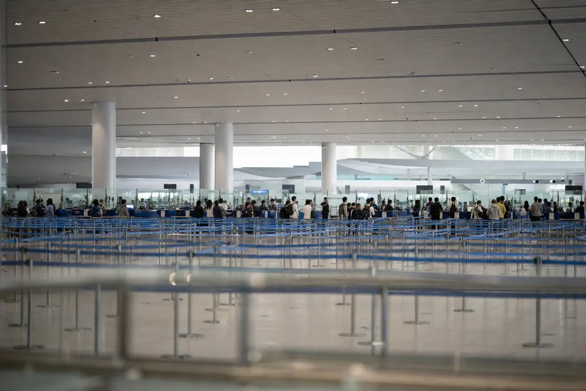 Queue lanes in an airport immigration hall with travellers waiting