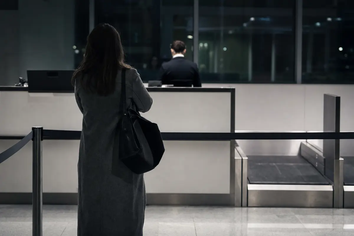 A passenger waiting at an airline check-in desk at night