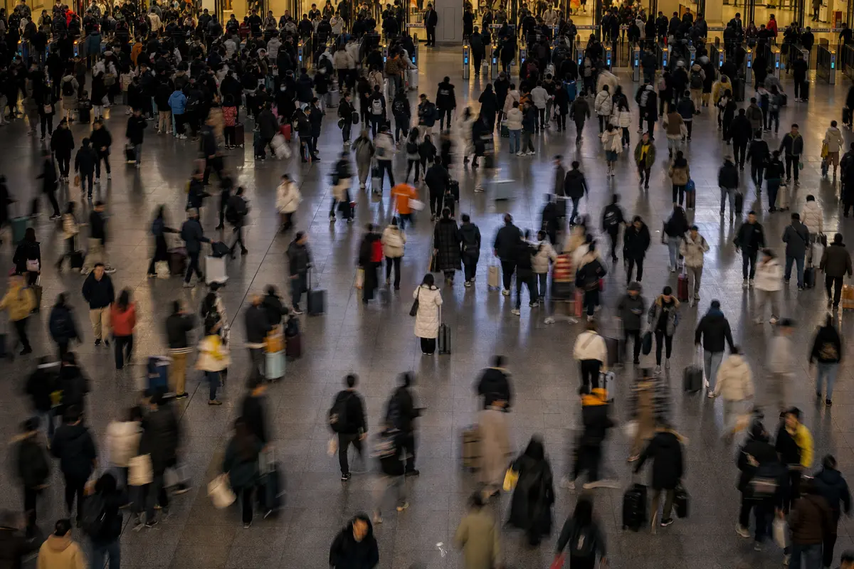 A crowded evening station concourse with motion blurred commuters