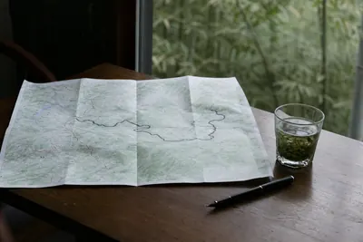A rail map, a pen and a cup of green tea on a table, with the route to the mountain marked