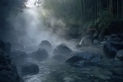 Steam rising off a rocky mountain stream at dawn below a bamboo slope