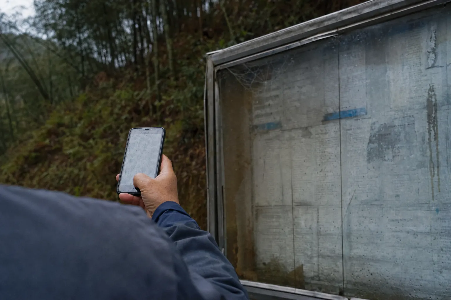 A phone held up in front of a printed Chinese notice board, screen glare washing out both