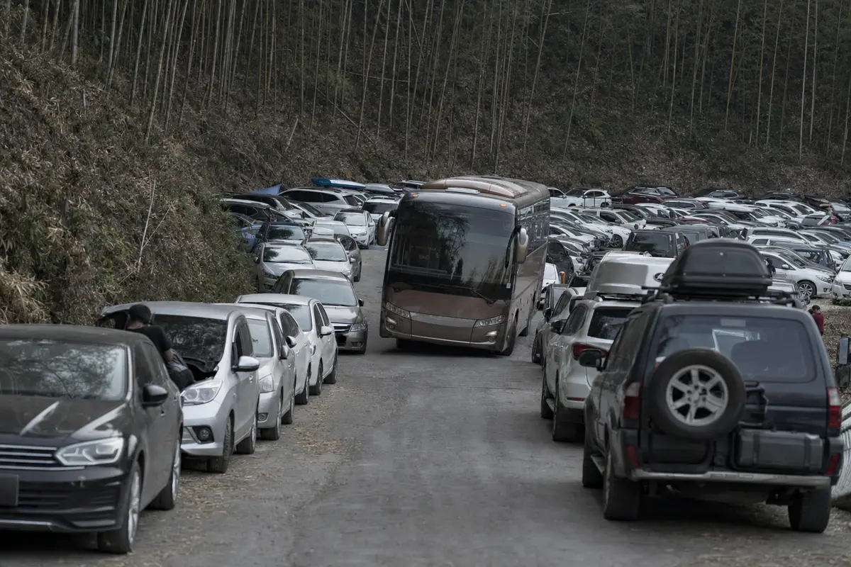 A completely full mountain car park with cars parked along both verges of the road