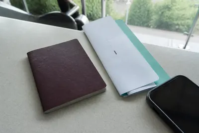 A passport, a boarding pass and a phone lying on an airport arrivals counter