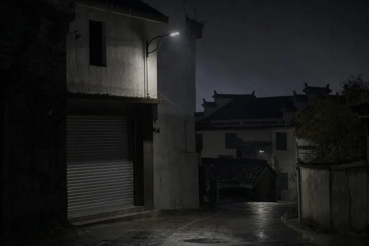 A closed shopfront and single street lamp on a wet village street after dark