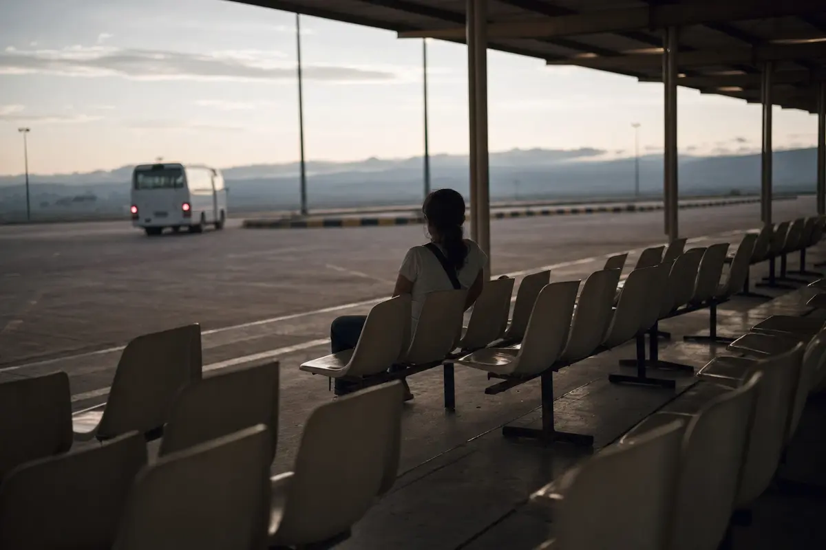 Empty seats under a canopy at a transfer centre as a shuttle pulls away