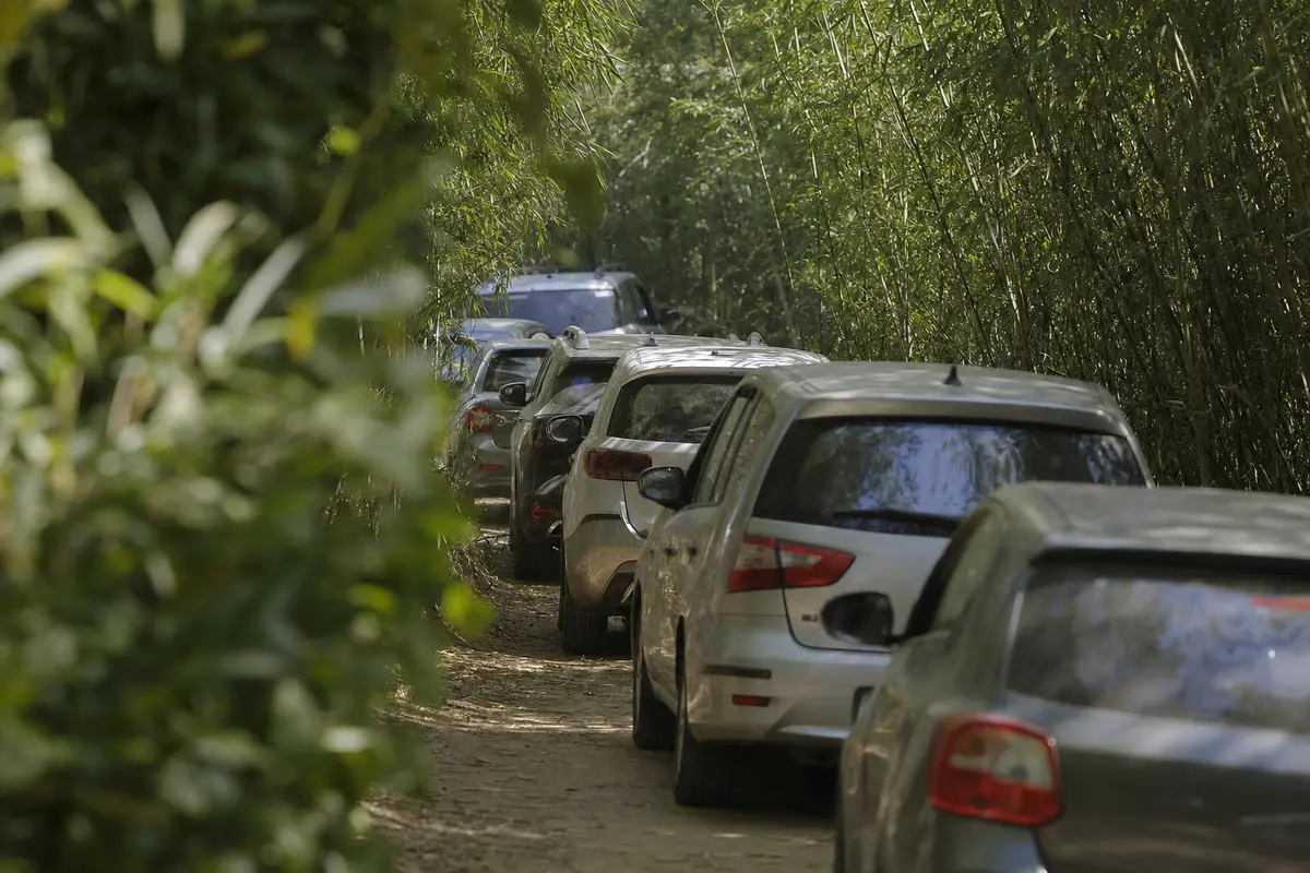 Cars stationary nose to tail on a narrow mountain road in bright heat