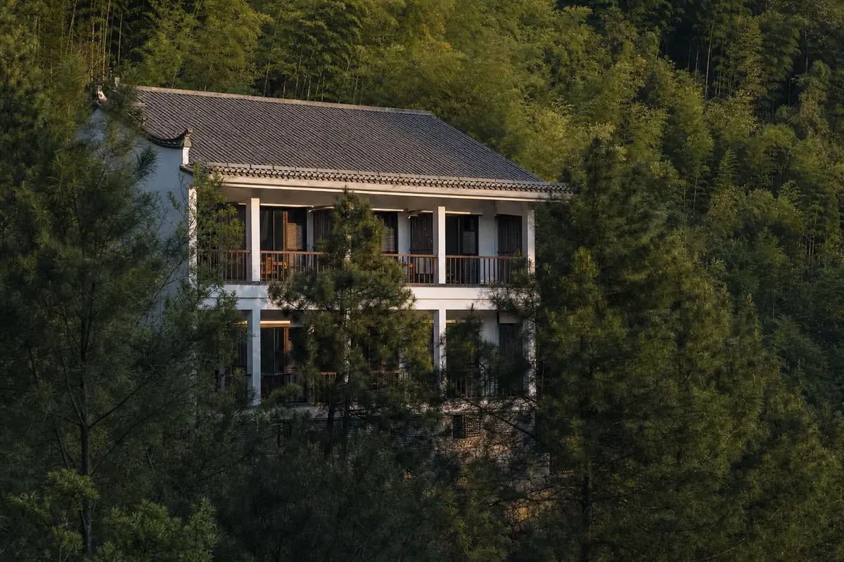 A white rendered hillside hotel with a two level colonnaded veranda and dark shutters