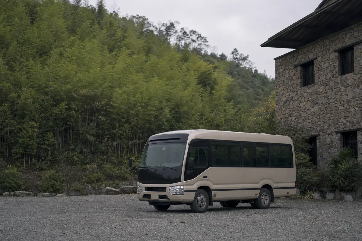 An unbranded shuttle vehicle waiting on a gravel forecourt below a stone building