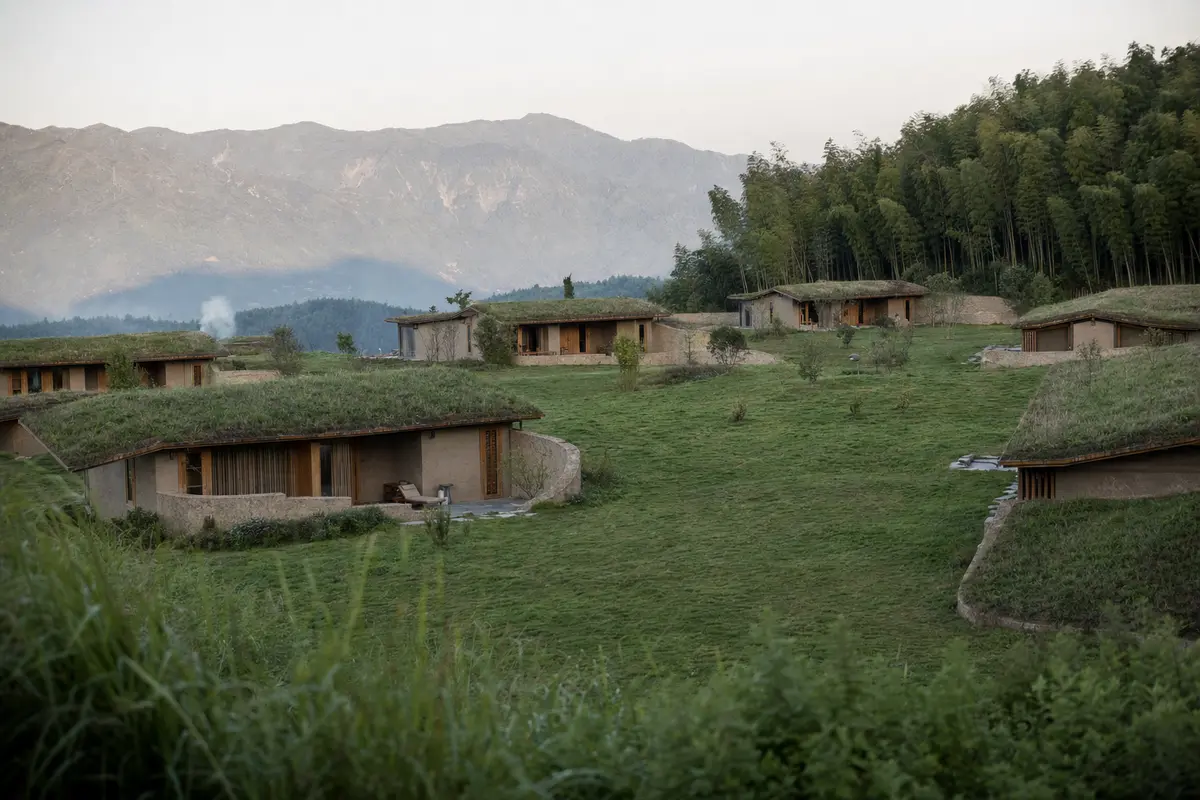 Low earth walled lodges with grass roofs spread across a grassy mountain plateau