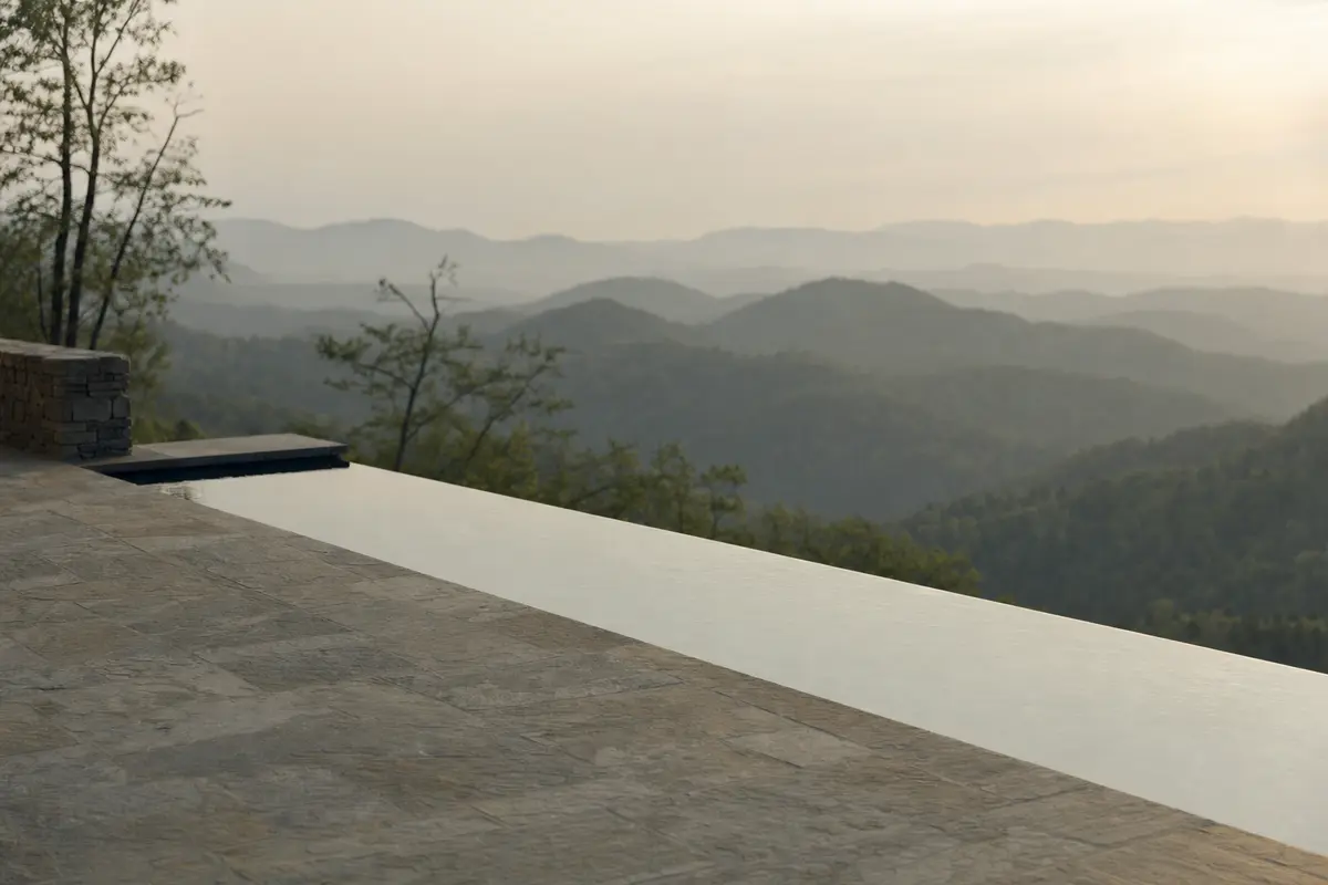 An infinity edge pool on a mountain terrace looking over layered forested ridges